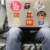 man using silver MacBook sitting on black leather sofa
