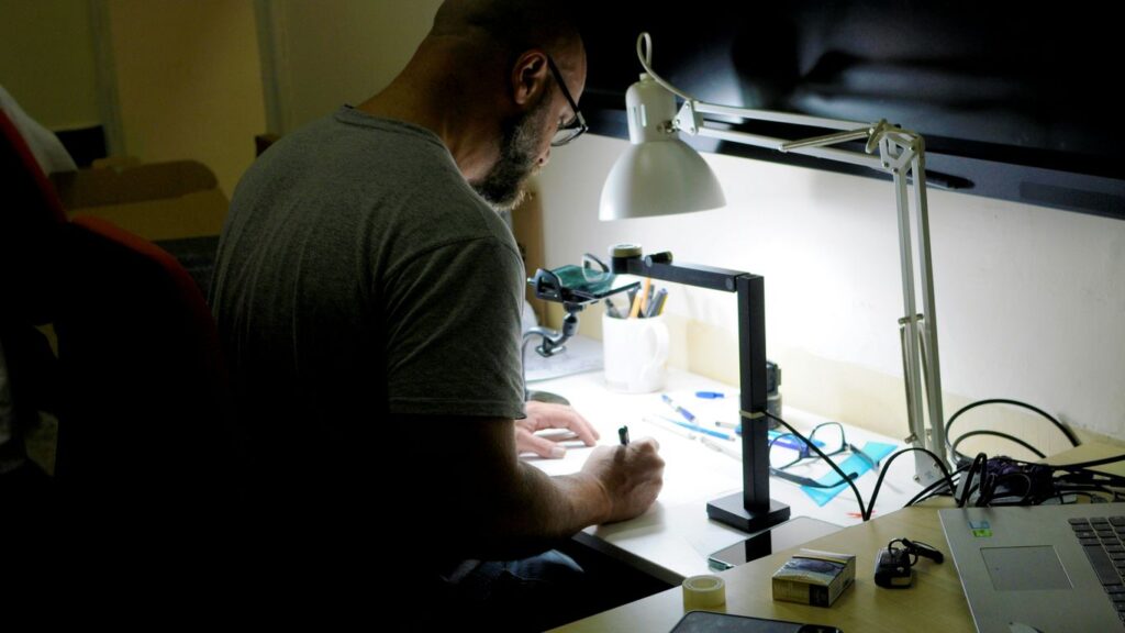 a man sitting at a desk writing on a piece of paper