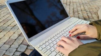 a woman is typing on her laptop outside