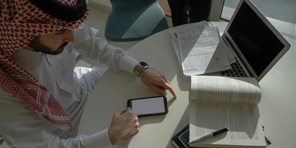 a man sitting at a table looking at a tablet