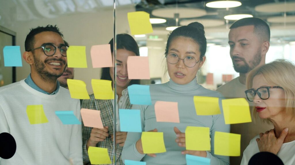 Team brainstorming with colorful sticky notes on glass.