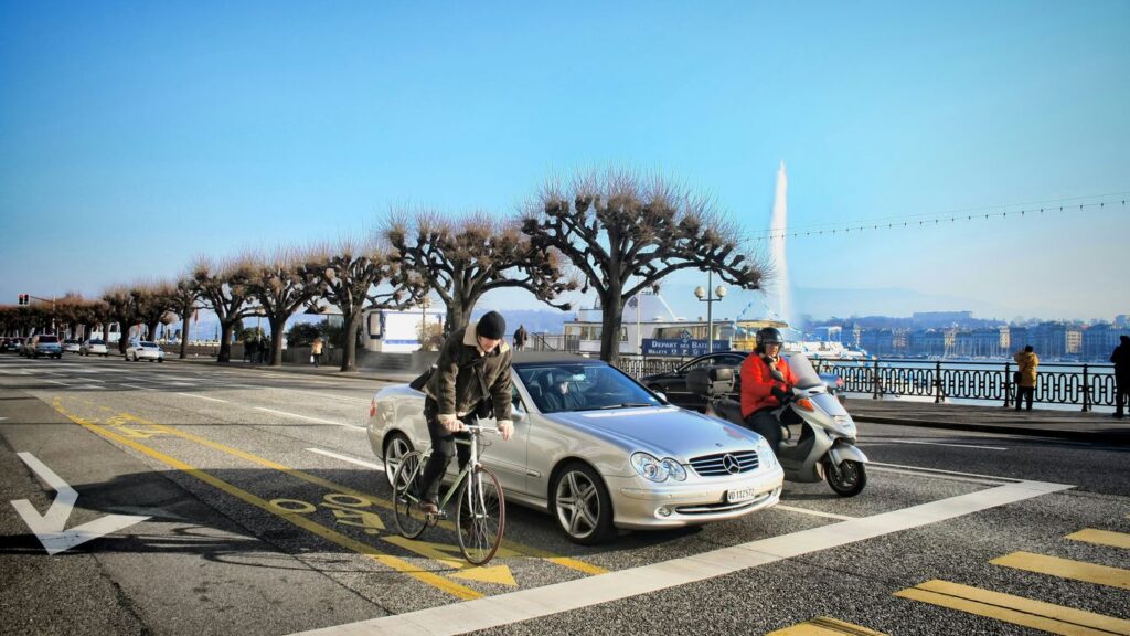 a man riding a bike next to a silver car