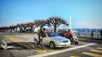 a man riding a bike next to a silver car