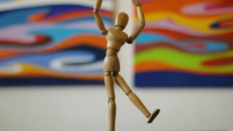 a wooden figure is posed in front of a painting