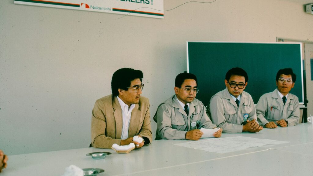 Four men sit at a table during a meeting.