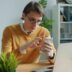 Man in yellow sweater using smartphone at desk