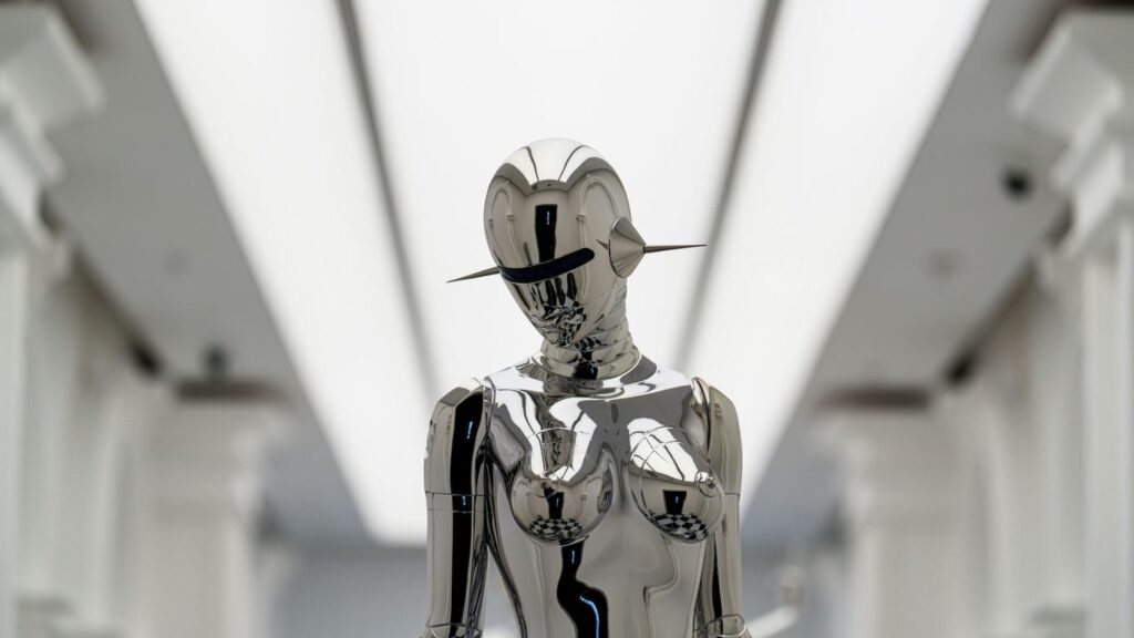 A futuristic silver sculpture stands.