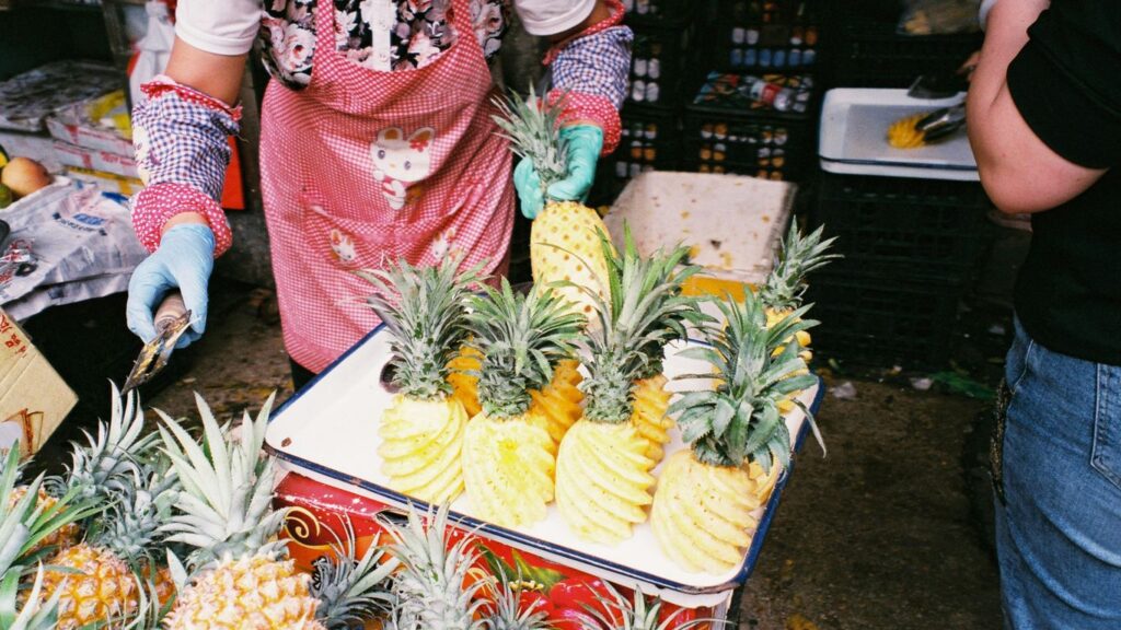 a woman in a pink apron and blue gloves standing next to a pile of pine