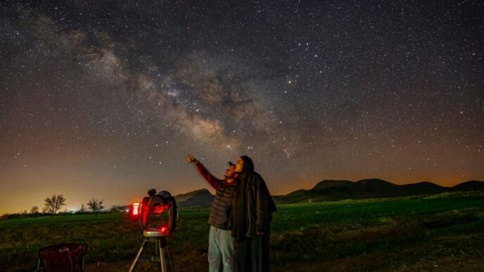 a man standing next to a telescope looking at the stars