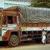 a man standing next to a truck with a tarp on it