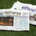 A newspaper laying on top of a lush green field