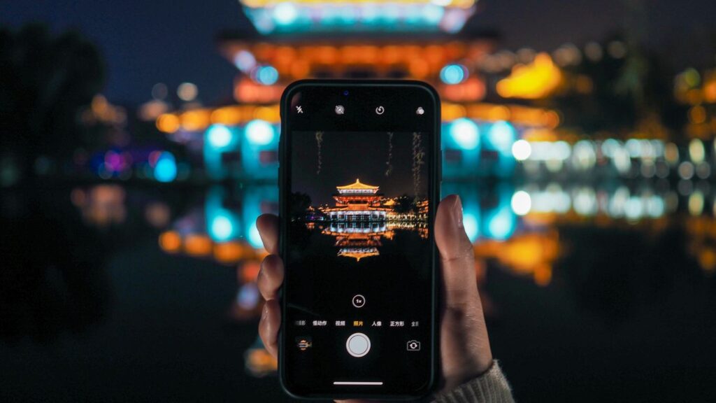 person holding iphone taking photo of yellow and white tower