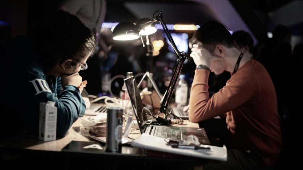 man in red long sleeve shirt sitting in front of table with laptop computer