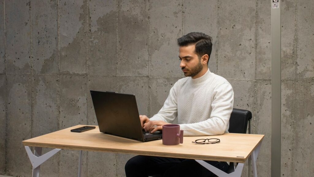 a man sitting at a table using a laptop computer