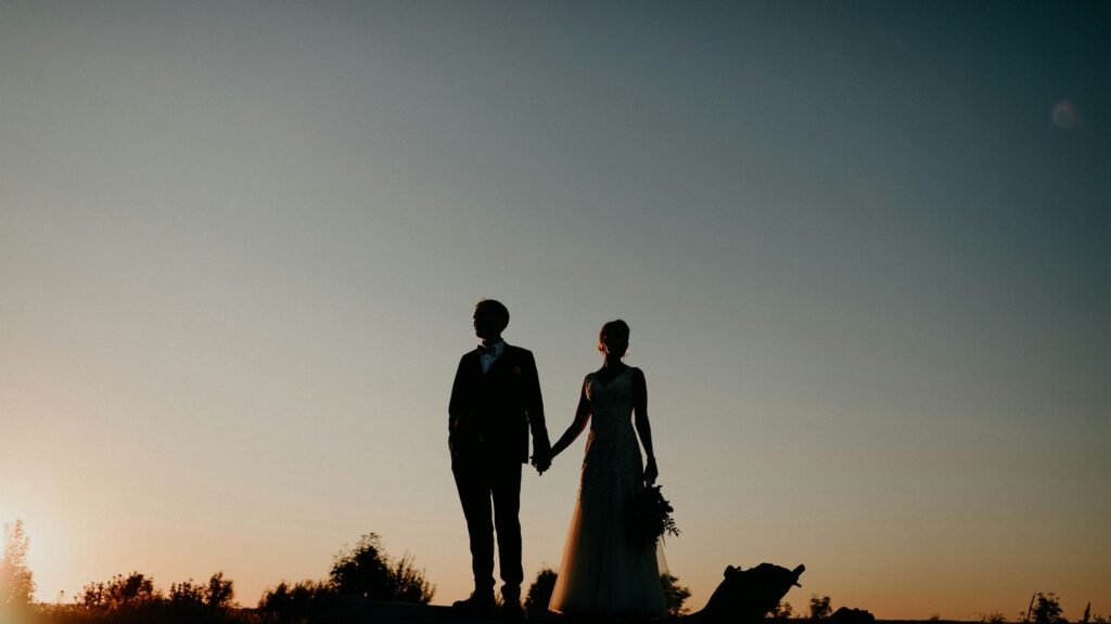 A bride and groom holding hands at sunset