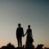 A bride and groom holding hands at sunset