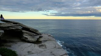 A person standing on top of a cliff next to the ocean
