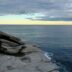 A person standing on top of a cliff next to the ocean