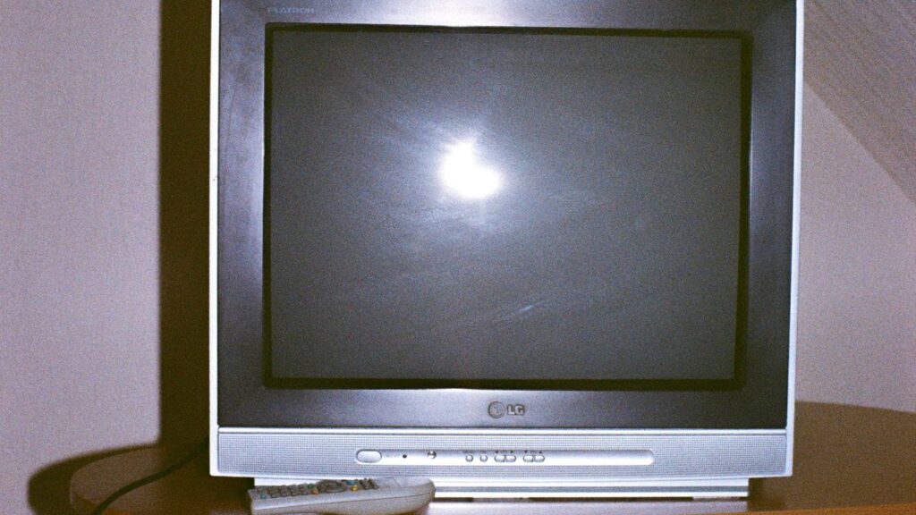 A television set with a remote control on a table.