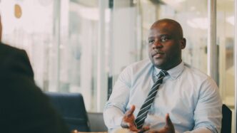Man in a light blue shirt and tie talking.