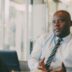 Man in a light blue shirt and tie talking.