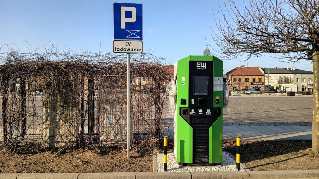 a green parking meter next to a parking sign