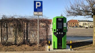 a green parking meter next to a parking sign