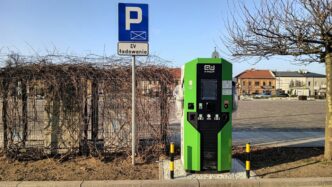 a green parking meter next to a parking sign