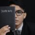 man in black suit holding black book