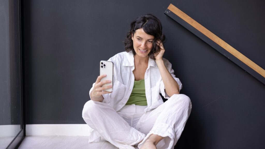 a woman sitting on the floor holding a cell phone
