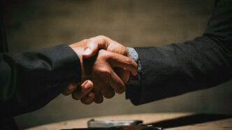 two people shaking hands over a wooden table