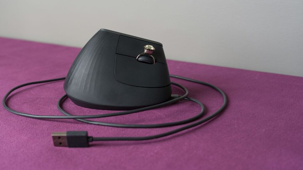 An ergonomic computer mouse rests on a purple surface.