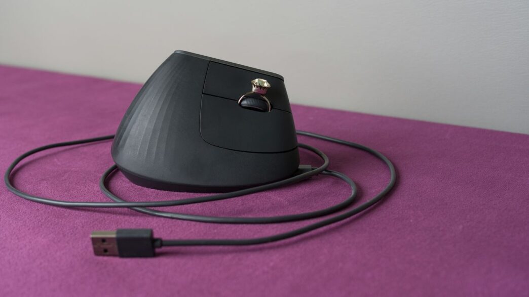 An ergonomic computer mouse rests on a purple surface.