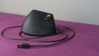 An ergonomic computer mouse rests on a purple surface.