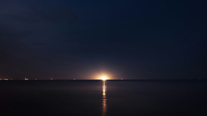 light post on the sea during night time