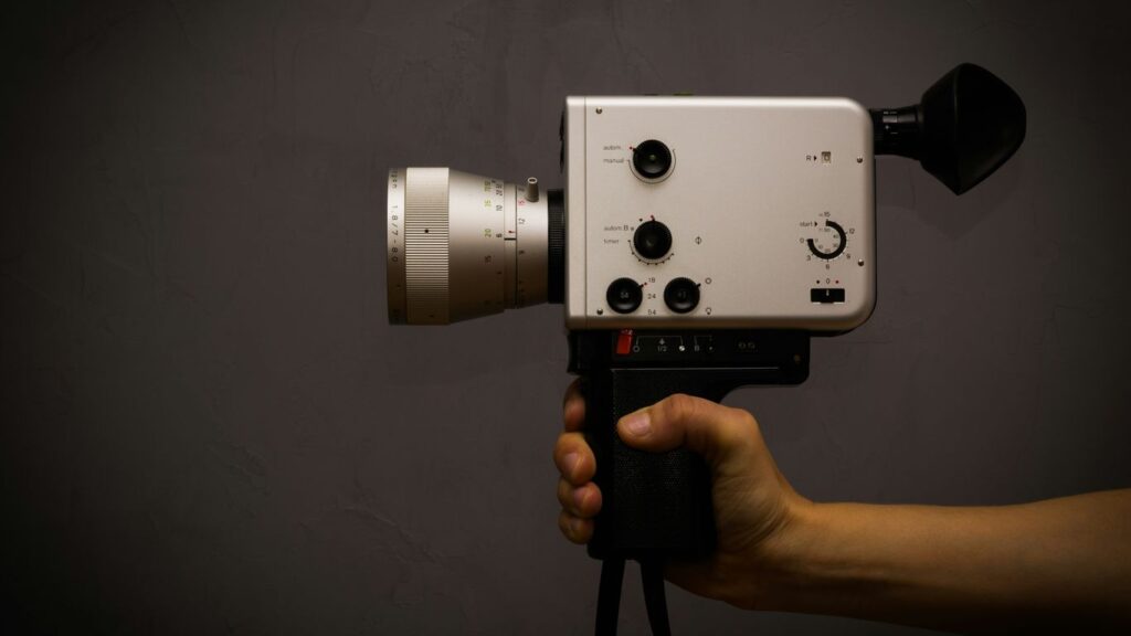 a hand holding a camera with a black background