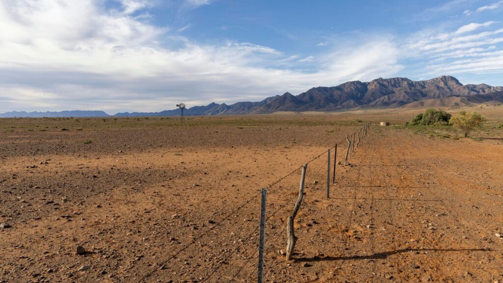 a fence in the middle of a desert with mountains in the background