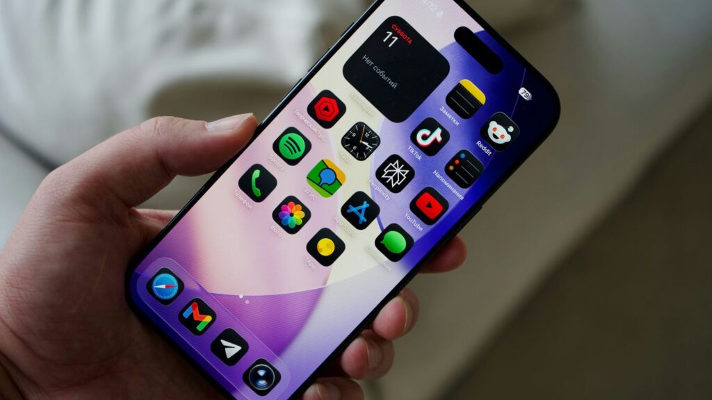 Hand holding a smartphone with colorful app icons.