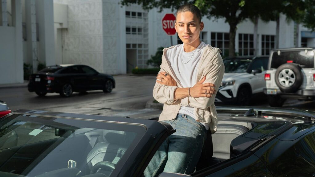 A man sitting on top of a car in a parking lot