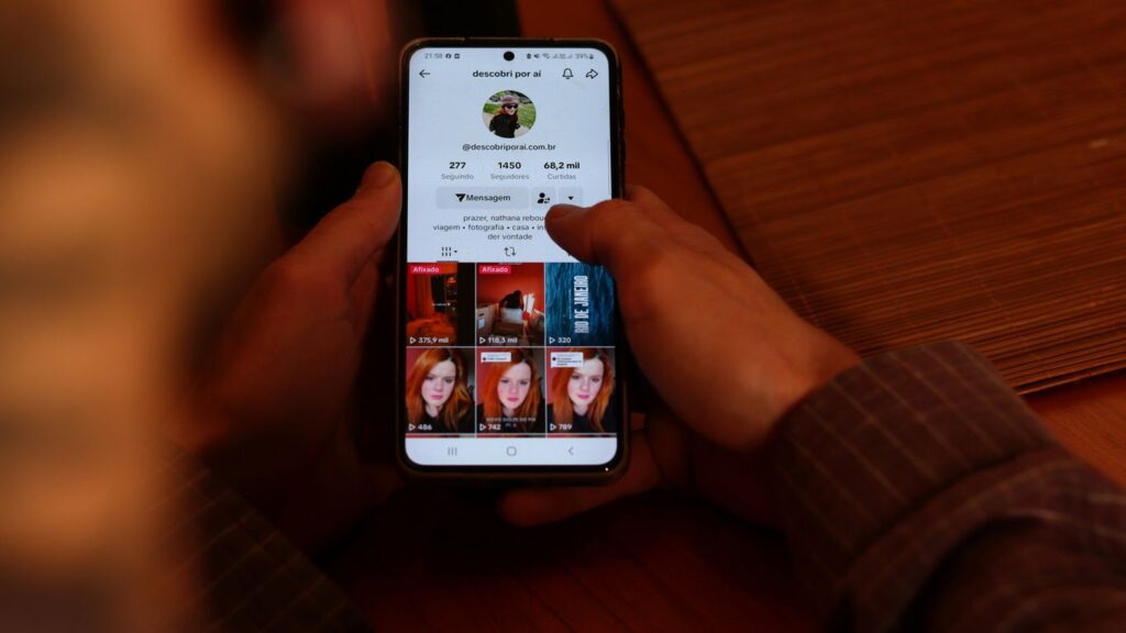 A person holding a cell phone with multiple pictures on the screen