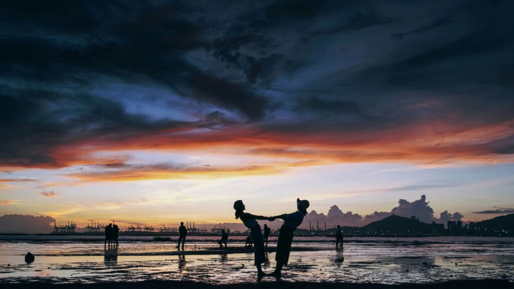 a group of people playing in the water at sunset