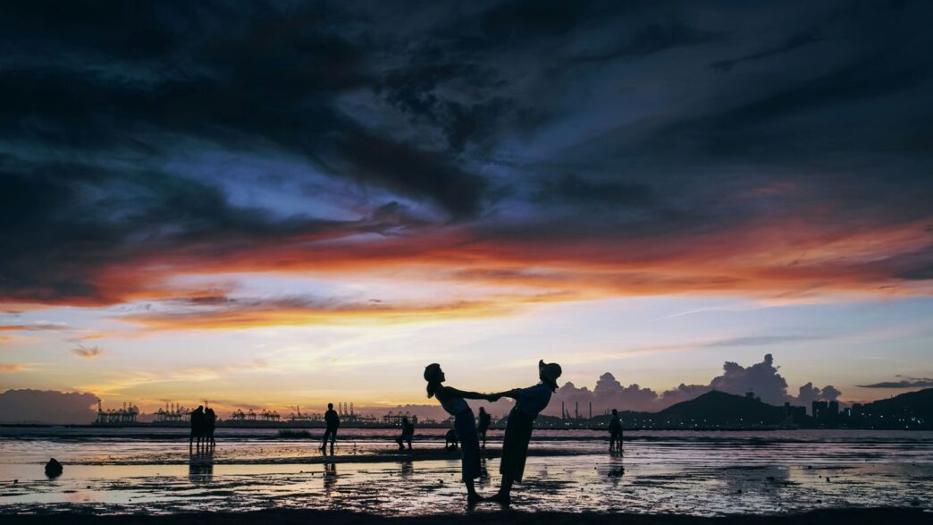 a group of people playing in the water at sunset