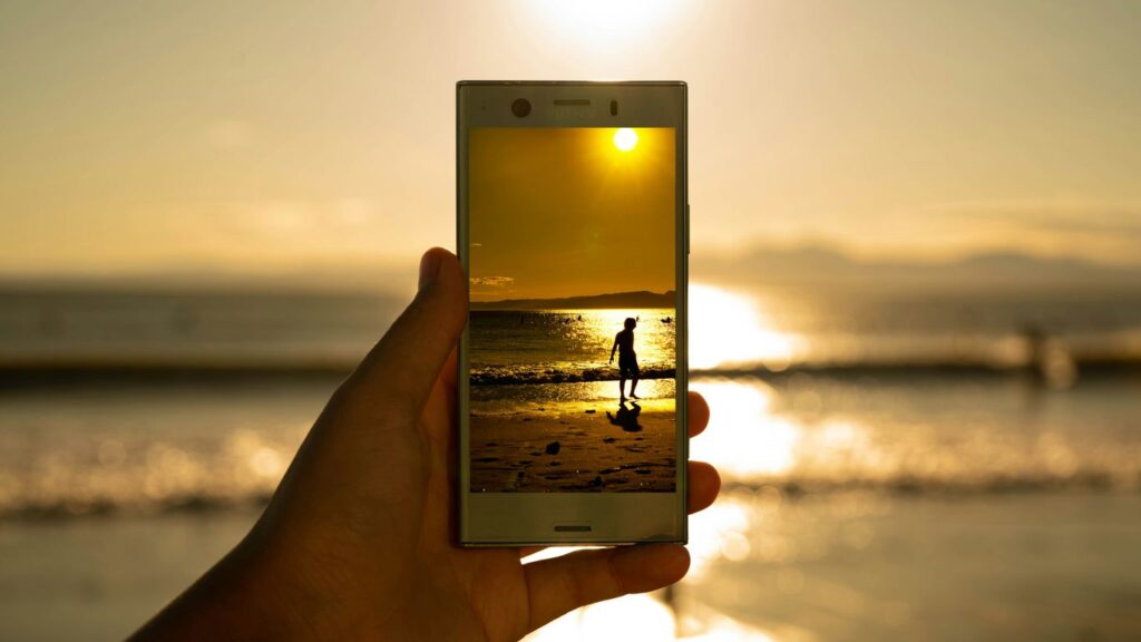 person holding phone showing person on seashore