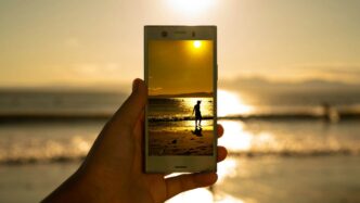 person holding phone showing person on seashore