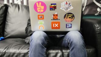 man using silver MacBook sitting on black leather sofa