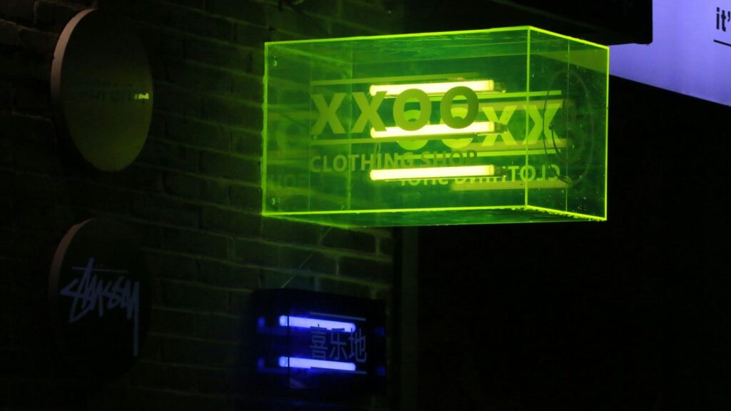 a neon sign hanging from the side of a brick building