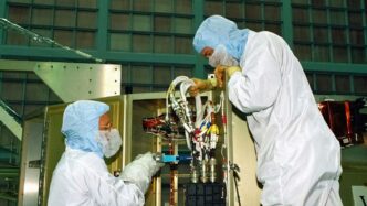 a couple of people in white suits working on a machine