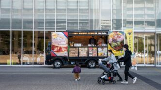 A group of people walking past a food truck