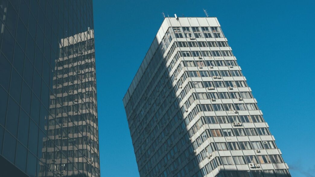 Skyscraper and its reflection under a clear blue sky.