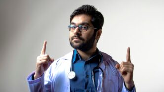 man in blue scrub shirt wearing black framed eyeglasses